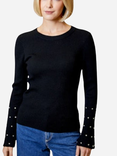 Black sweater with studded details on long sleeves worn by a person against a white background