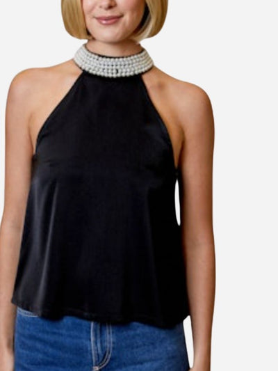 Woman wearing a black halter top and blue jeans with a pearl collar on a white background