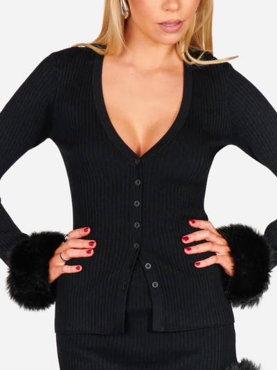 Black cardigan with fur cuffs worn by a model on a white background