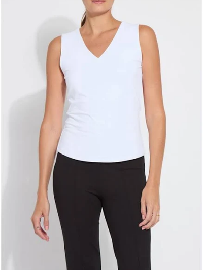 Woman wearing a white sleeveless top and black pants on a plain background