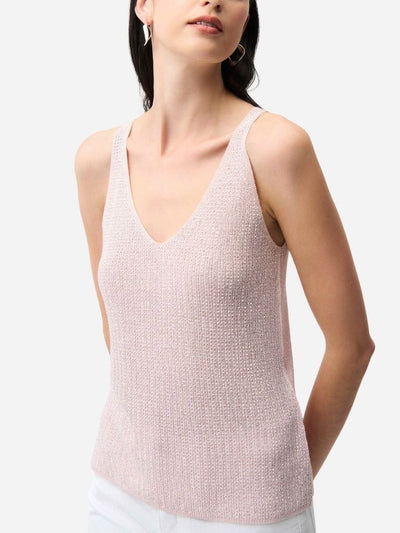 Woman wearing a light pink sleeveless top against a white background