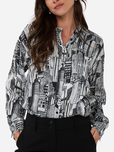 Person wearing a black and white patterned shirt with hands in pockets on a white background