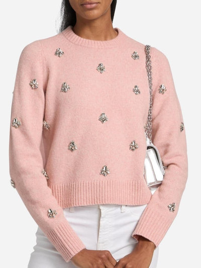 Pink sweater with sequin embellishments worn by a woman on a white background