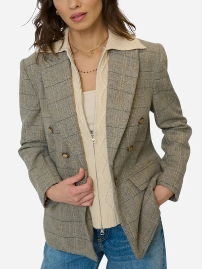 Woman wearing a plaid blazer over a cream dickey sweater with a white background