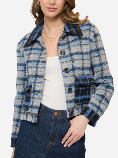 Woman wearing a blue and beige plaid jacket on a white background