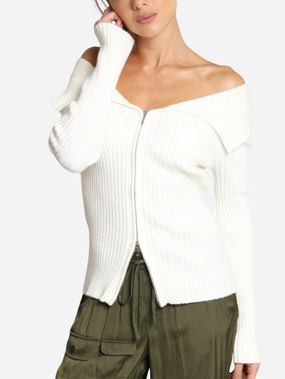 Woman wearing a white ribbed sweater and green pants on a white background