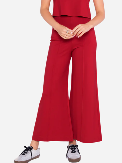 Woman wearing red wide-leg cropped pants on a white background