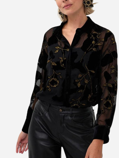 Black sheer blouse with floral embroidery worn by a person on a white background