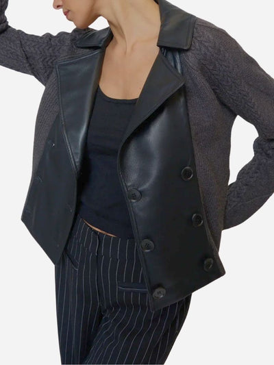 Person wearing a black leather jacket over a gray sweater on a white background