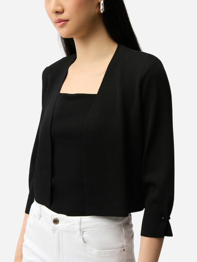 Person wearing a black cardigan with a plain background