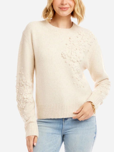 Woman wearing a cream sweater and light blue jeans on a white background