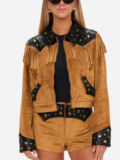 Woman wearing a tan suede jacket with black leather accents and fringes on a white background