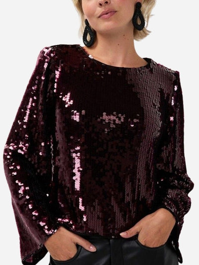 Person wearing a dark red sequin top with a plain background