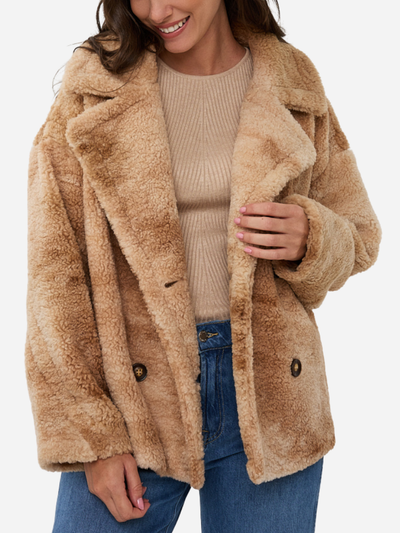 Woman wearing a beige sherpa coat on a white background