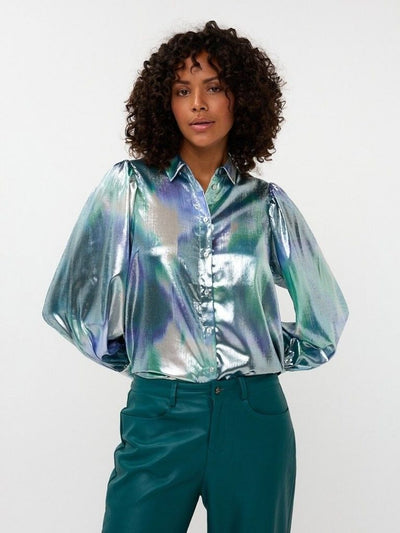 Person wearing a reflective silver shirt and teal pants on a white background