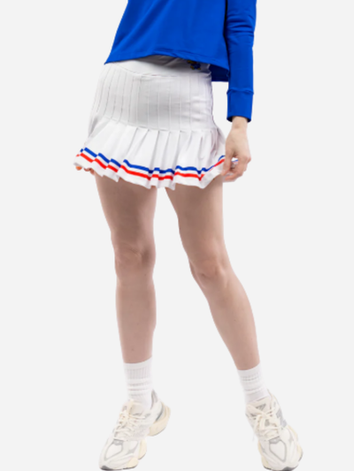 Person wearing a blue top, white skirt with red and blue trim for K.U., and white sneakers on a white background