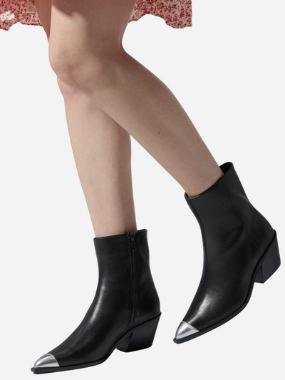 Black ankle boots with silver accents worn by a person on a white background