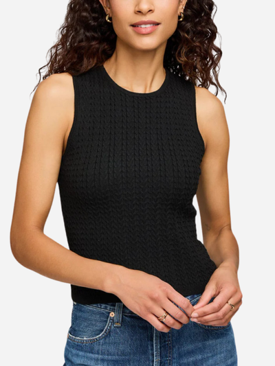 Woman wearing a black sleeveless knitted top and blue jeans on a white background