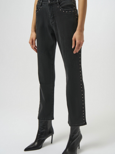Black jeans with studded details worn by a woman on a white background