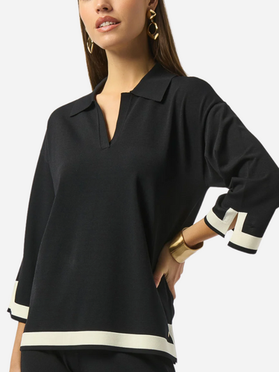 Black blouse with white trim worn by a model on a white background