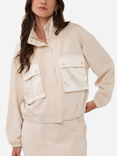 Woman wearing a cream bomber jacket with large pockets on a white background