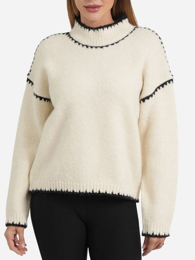 Cream-colored sweater with black trim worn by a woman on a white background