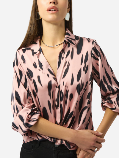 Woman wearing a pink blouse with black animal print pattern on a white background