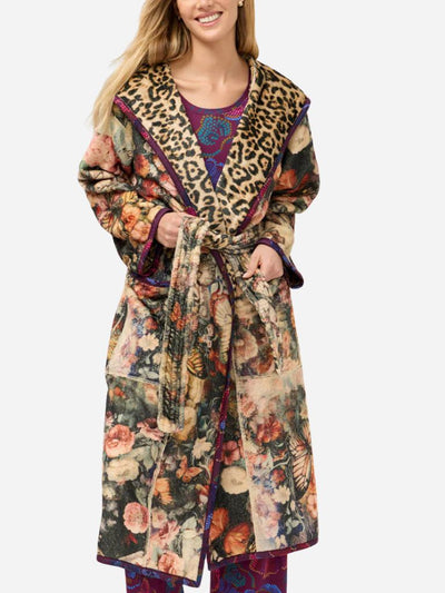 Woman wearing a colorful floral robe with a leopard print collar on a white background