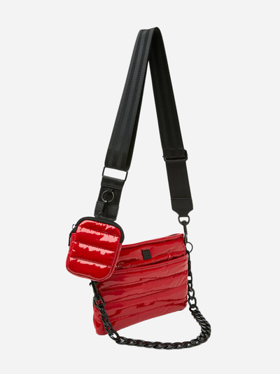 Red quilted handbag and crossbody with a black strap on a white background