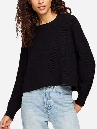 Person wearing a black sweater and light blue jeans on a white background