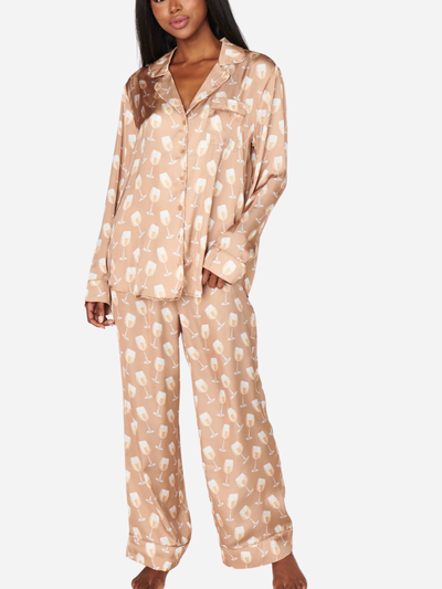 Woman wearing a beige pajama set with a subtle wine glass pattern on a white background