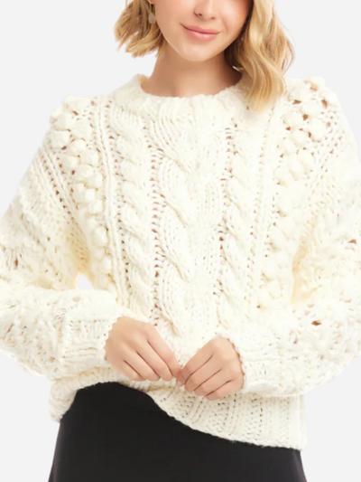 Person wearing a white chunky knit sweater on a plain background