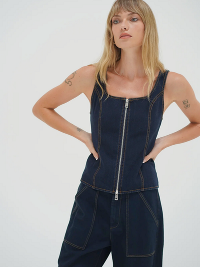 Woman wearing a dark denim vest with a zipper